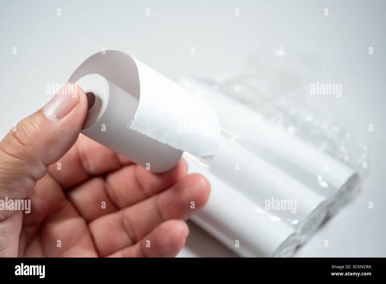 Main tenant un rouleau de papier thermique, symbolisant le contact direct de la peau avec le revêtement chimique du papier, qui peut contenir du BPA (bisphénol A) Banque D'Images