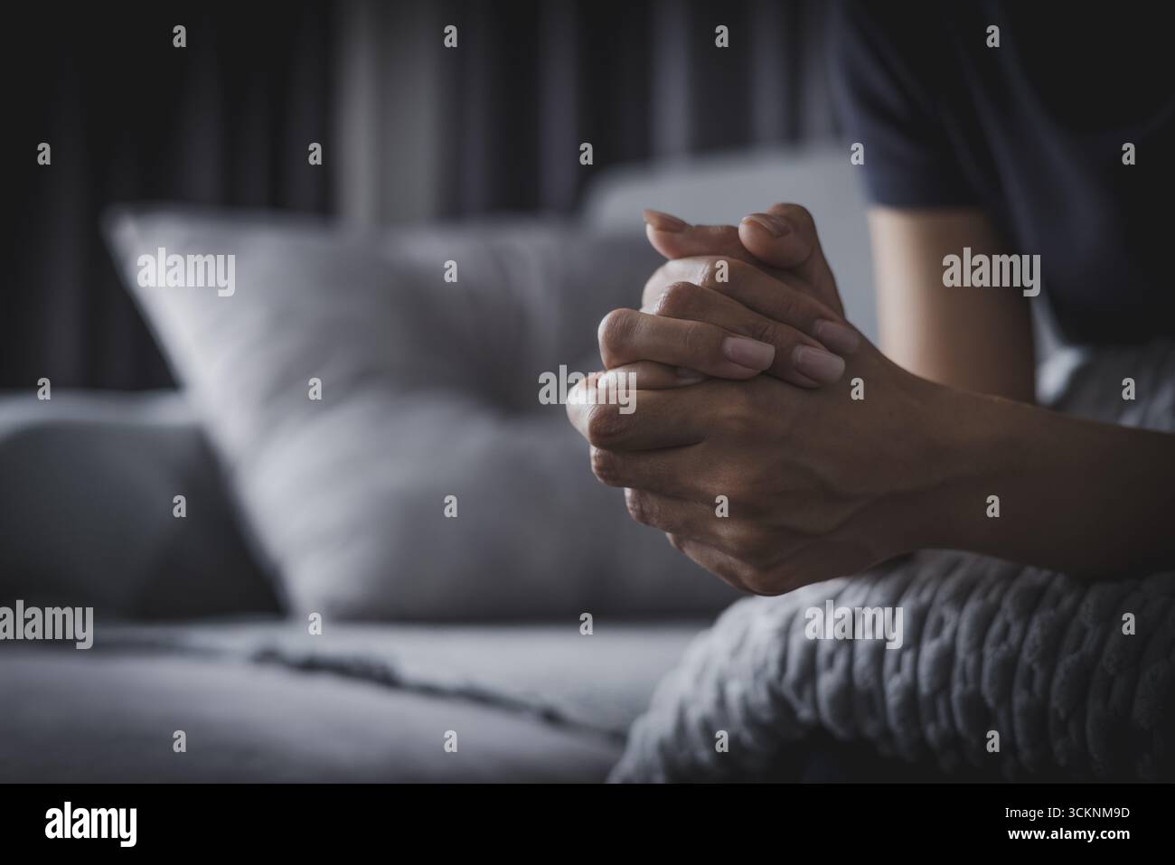 les mains de la femme se serrèrent dans un moment de prière ou de contemplation profonde mettant en valeur les pensées intérieures. Banque D'Images