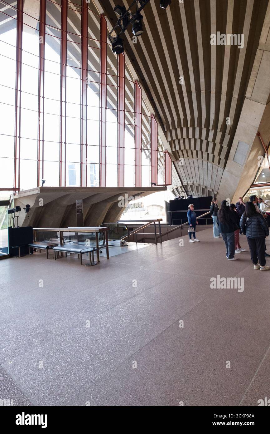Les visiteurs visitent le vaste espace intérieur de l'Opéra de Sydney, doté d'un plafond en béton distinctif et de grandes fenêtres, Sydney Banque D'Images