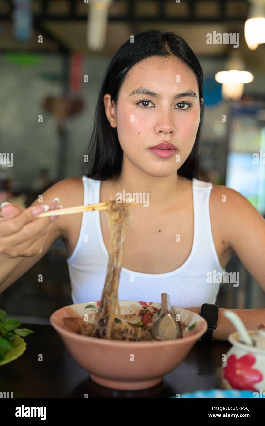 Belle jeune femme thaïlandaise mangeant les célèbres nouilles de bateau de nourriture de rue de Thaïlande servies au restaurant local Banque D'Images
