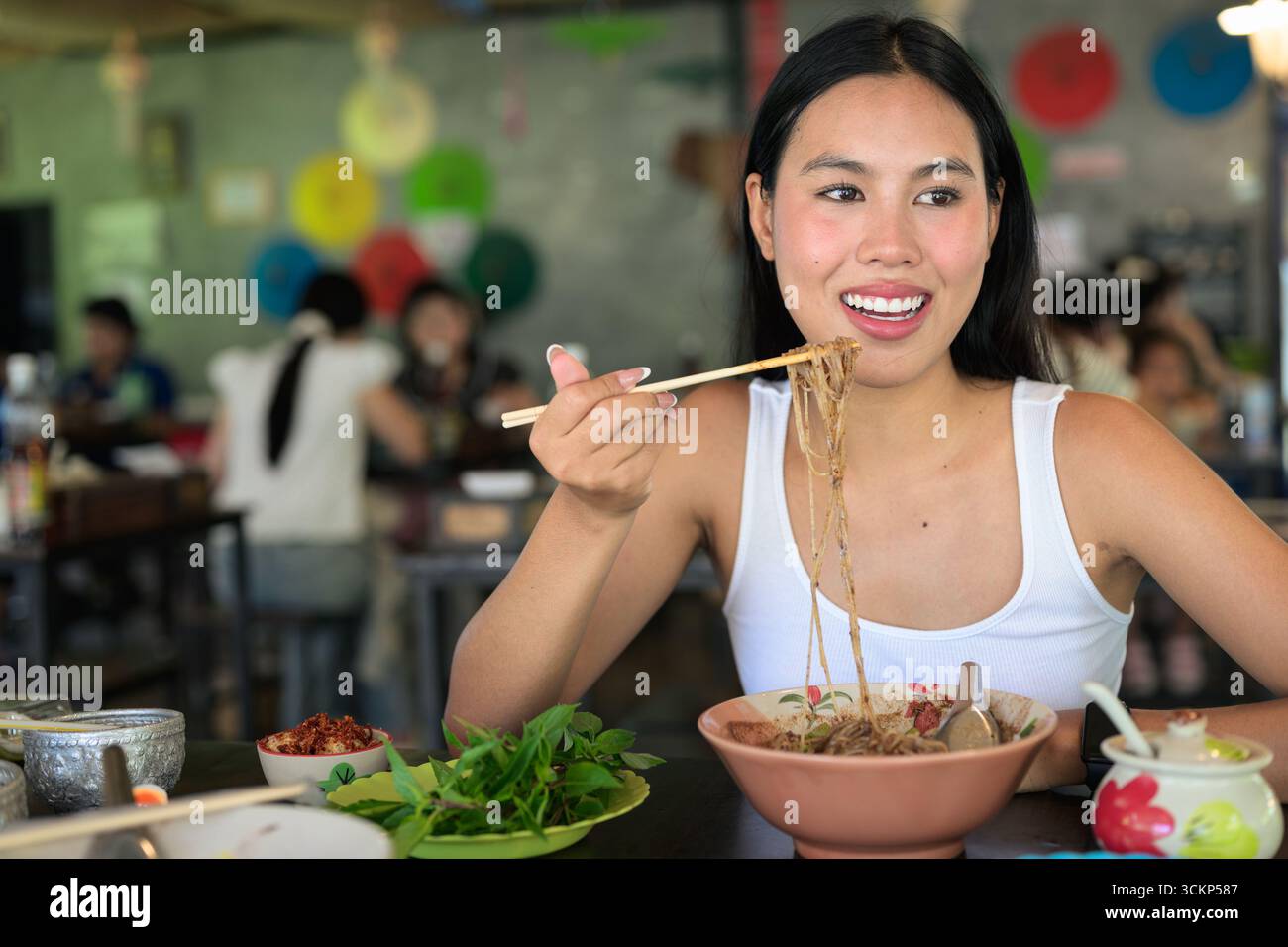 Belle jeune femme thaïlandaise mangeant les célèbres nouilles de bateau de nourriture de rue de Thaïlande servies au restaurant local Banque D'Images