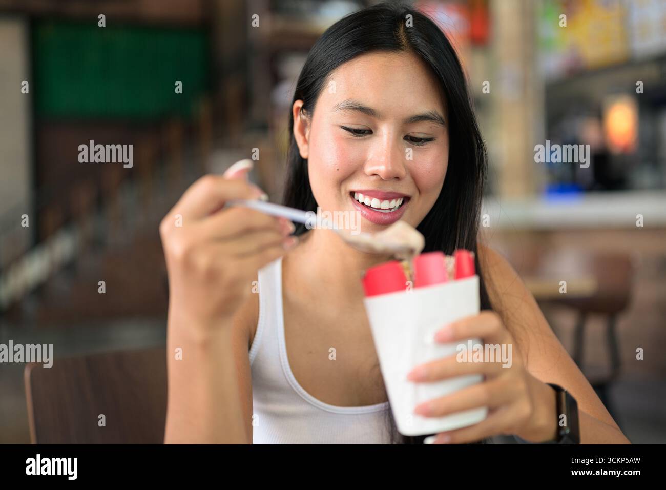 Jeune belle femme asiatique assise et mangeant de la crème glacée au restaurant Banque D'Images