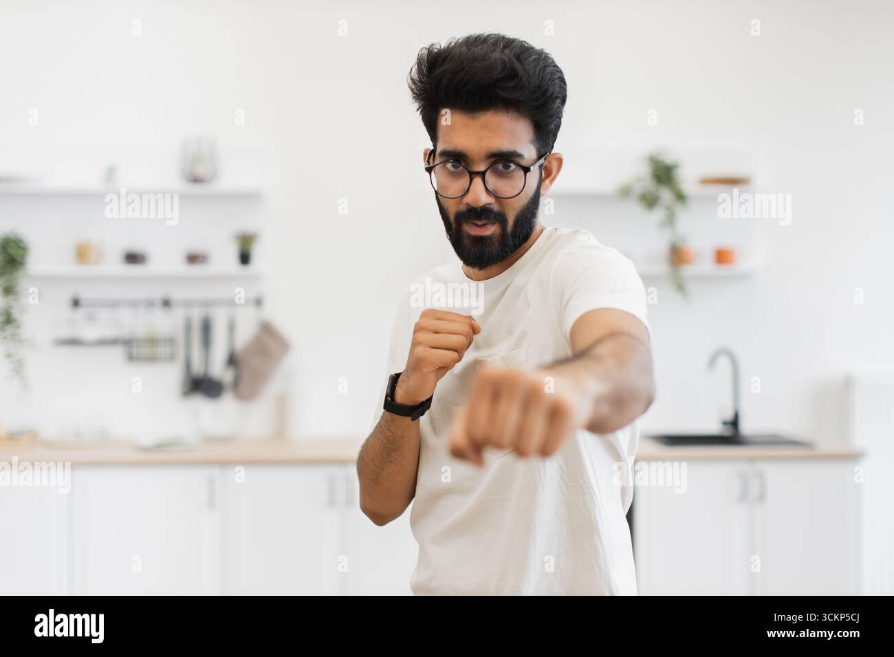 Homme pratiquant les techniques de boxe dans un environnement de cuisine avec détermination Banque D'Images