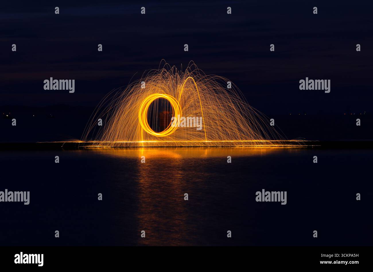 Profitez de feux d'artifice avec de la laine d'acier sur la plage dans l'obscurité de la nuit Banque D'Images