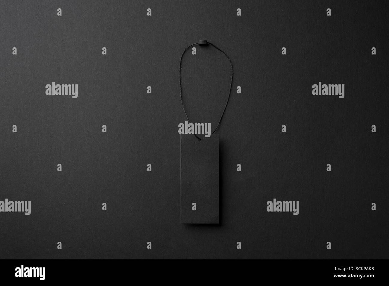 Étiquette de vêtements en carton noir minimaliste avec ficelle sur fond sombre Banque D'Images