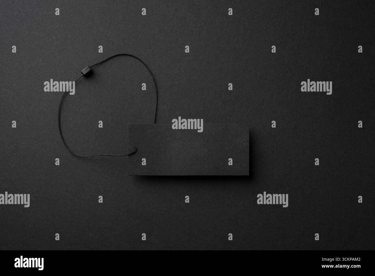 Étiquette de vêtements en carton noir minimaliste avec ficelle sur fond sombre Banque D'Images