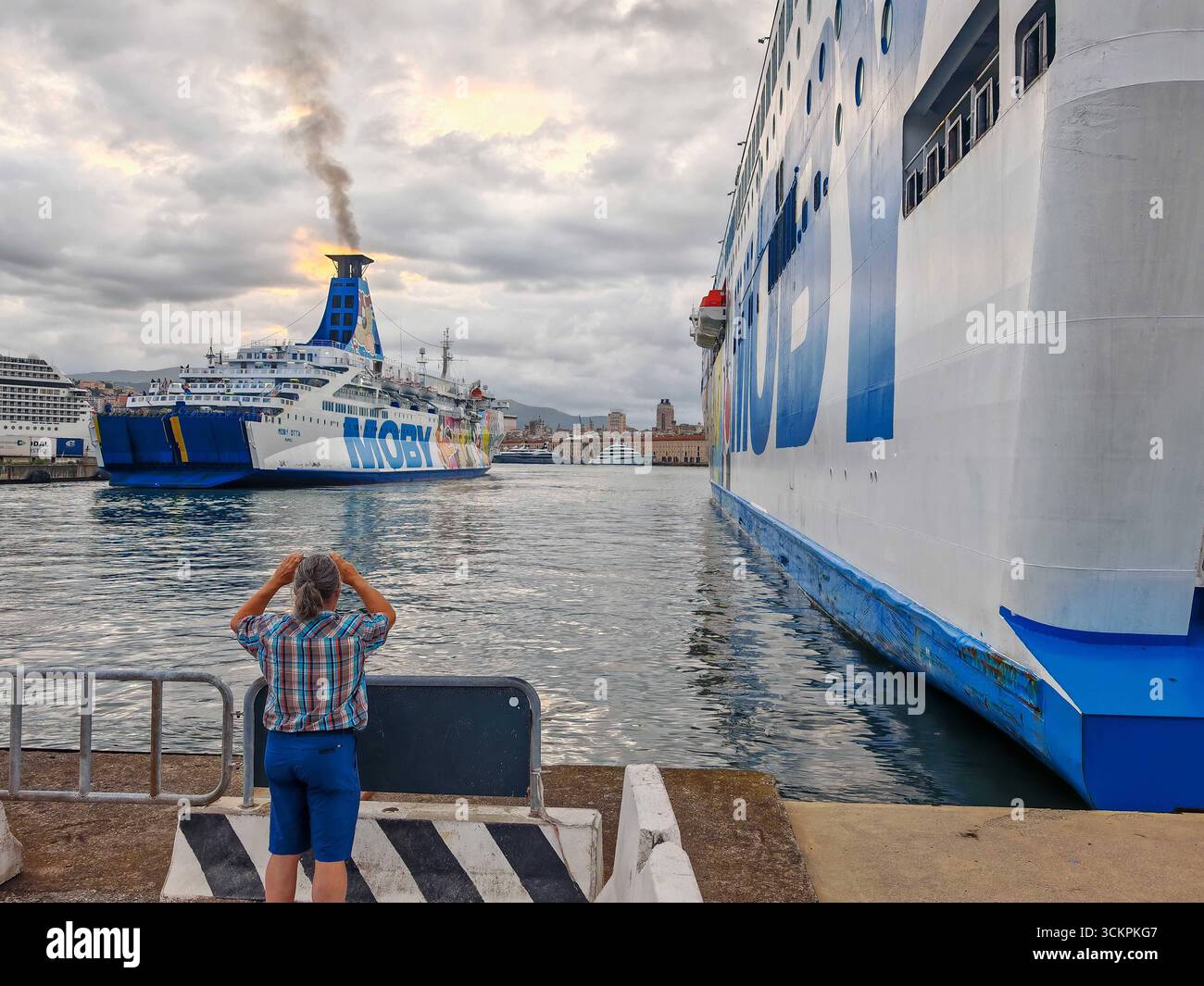 Gênes, Italie - 13 septembre 2025 : un touriste prend une photo du ferry Moby Otta au départ du port de Gênes. Le navire à passagers et RoRo exploité par la compagnie maritime MOBY relie les villes portuaires de la Méditerranée et transporte des véhicules *** Ein Tourist fotografiert die Autofähre Moby Otta BEI der Abfahrt aus dem Hafen von Genua. DAS Passagier- und RoRo-Schiff der Reederei Moby verbindet Hafenstädte im Mittelmeer und transportiert Fahrzeuge Banque D'Images