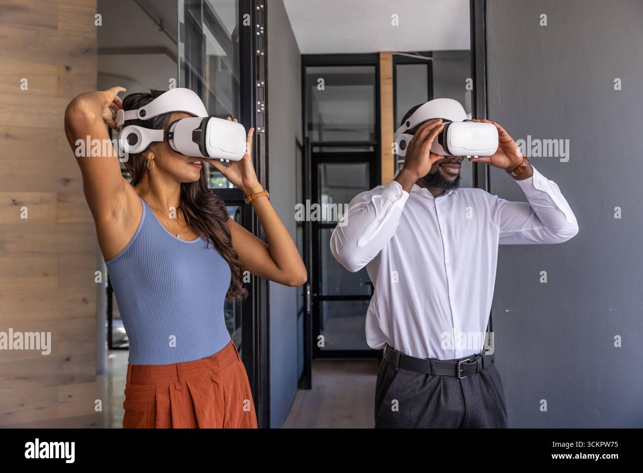Divers collègues ajustent les casques de réalité virtuelle dans un couloir de bureau moderne Banque D'Images