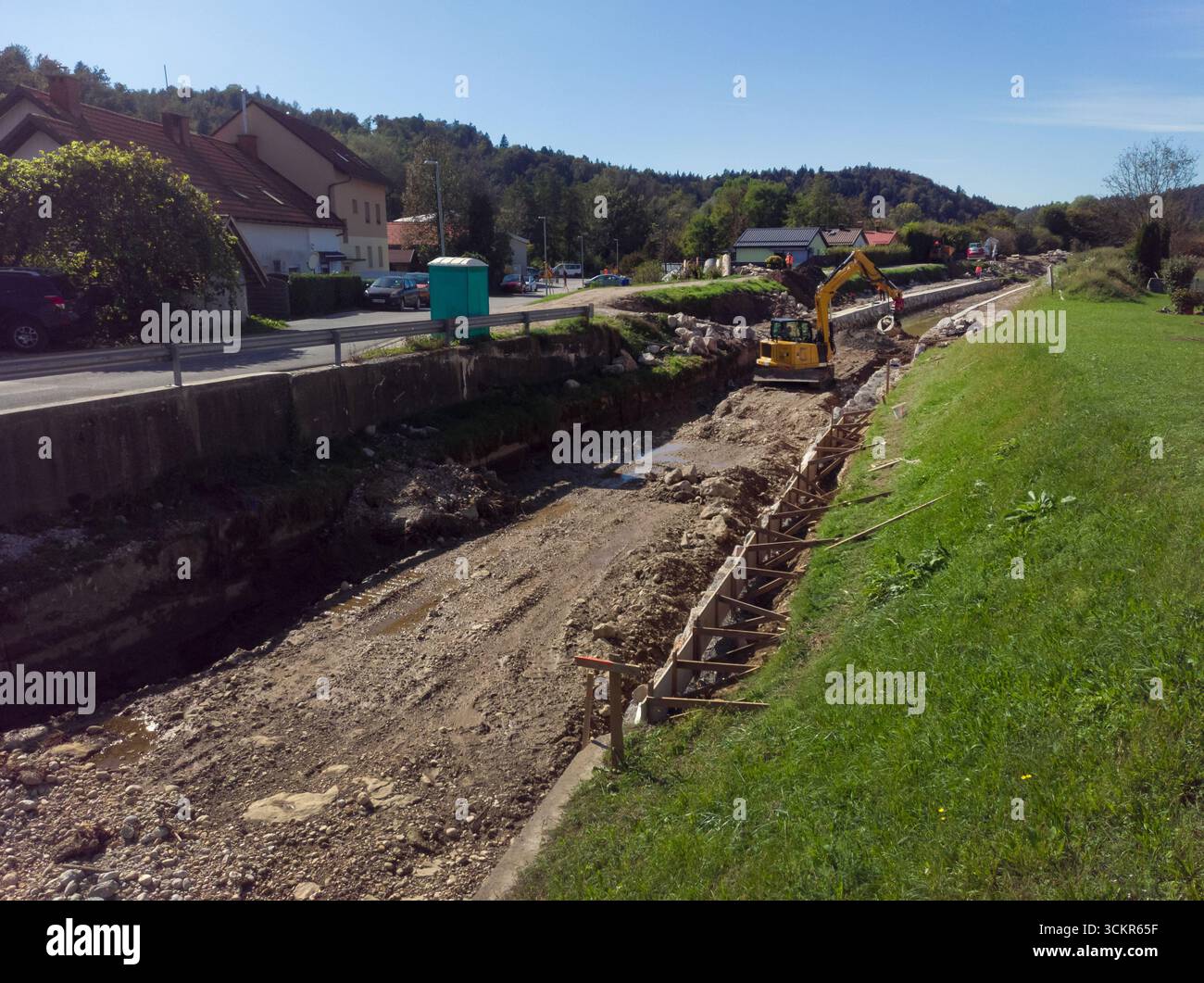 Les ouvriers utilisent des machines pour approfondir le canal fluvial, améliorant ainsi le débit d'eau dans une zone rurale sous ciel dégagé. Banque D'Images