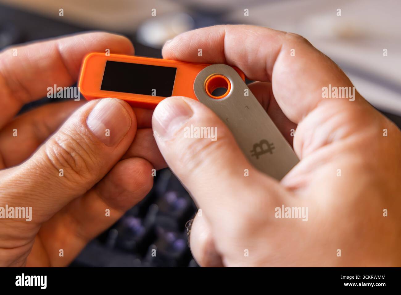 Portefeuille Bitcoin matériel tenu dans des mains blanches avec écran vierge Banque D'Images