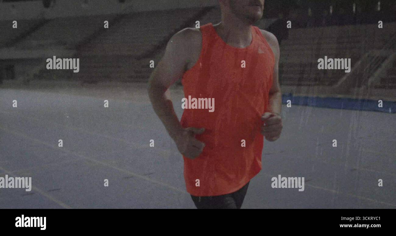 Athlète de course portant un maillot orange, un short sur une piste bleue au stade avec des stands vides, un espace de copie Banque D'Images