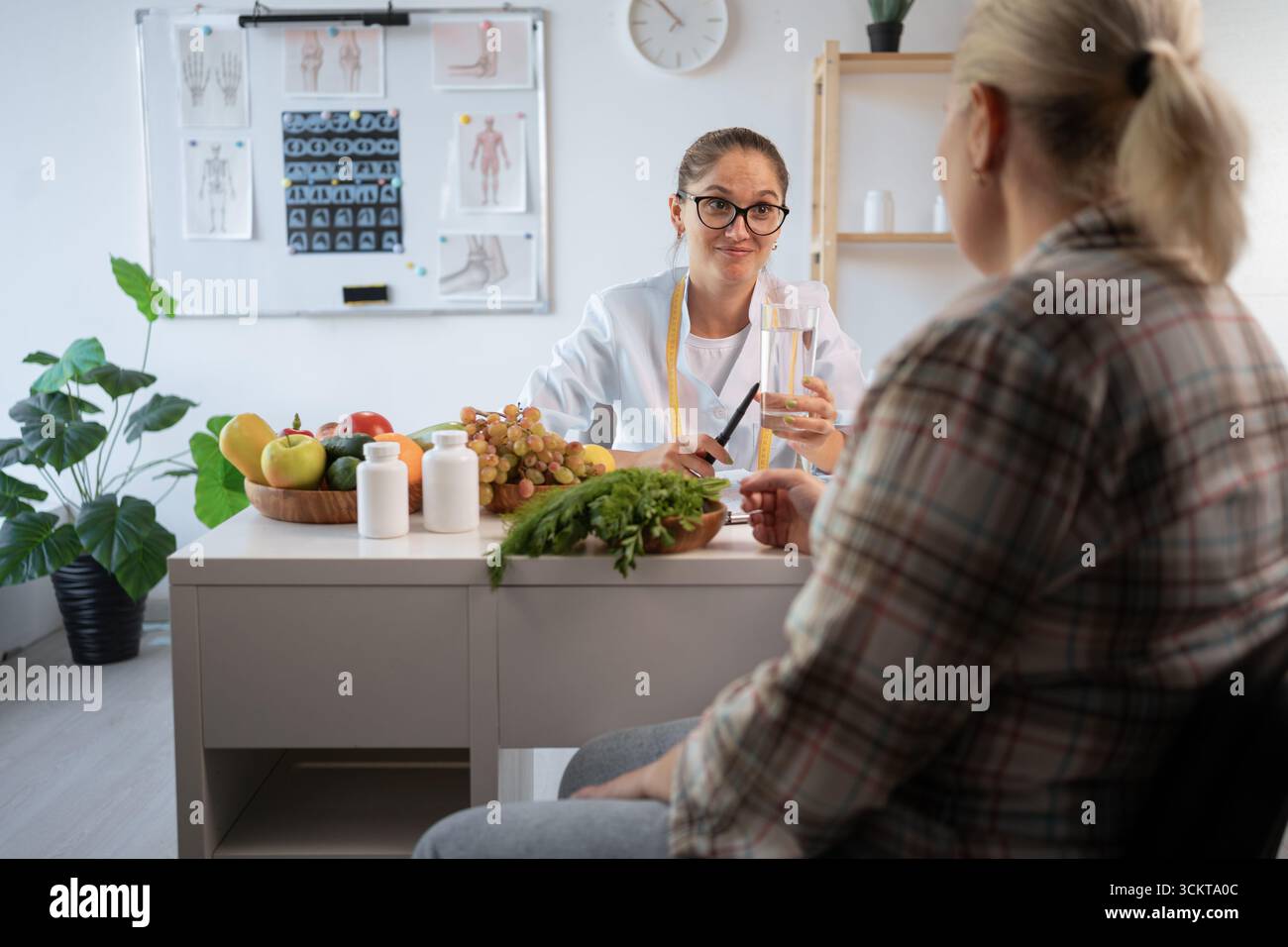 Concept de perte de poids. Jeune nutritionniste consultant femme en surpoids parlant de plan de repas et de produits sains assis dans la clinique. copier l'espace Banque D'Images