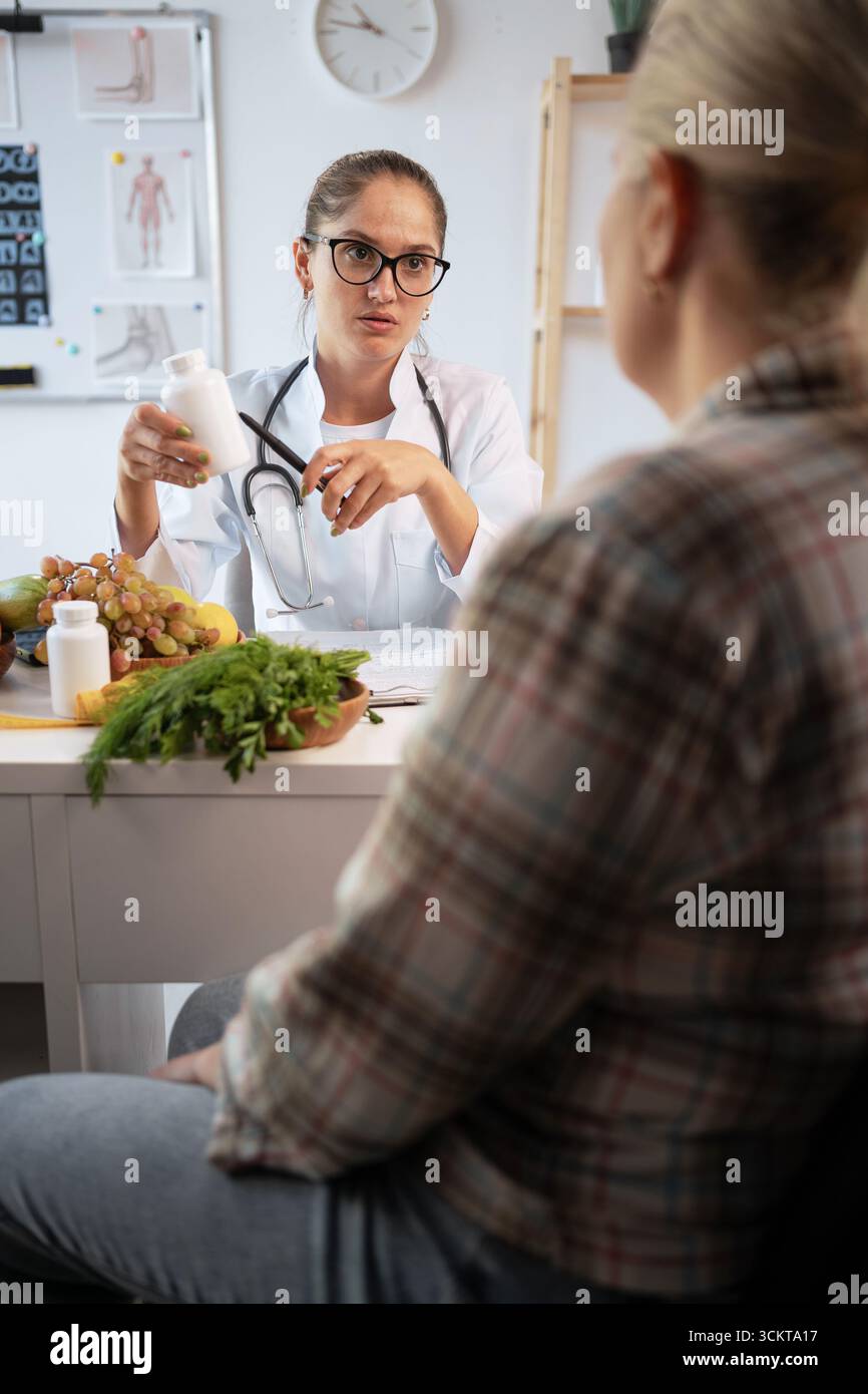 Médecine, traitement, nutrition et concept de régime. Femme caucasienne nutritionniste consultant patient en surpoids tenant des pilules ou des vitamines dans les mains et GI Banque D'Images