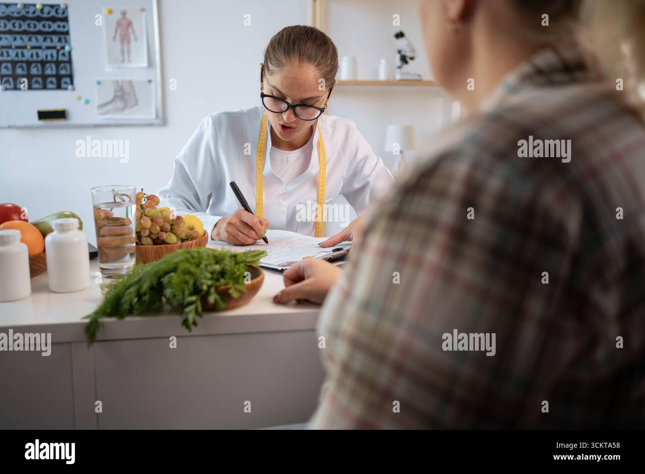 Concept de perte de poids. Jeune nutritionniste consultant femme en surpoids parlant de plan de repas et de produits sains assis dans la clinique. copier l'espace Banque D'Images