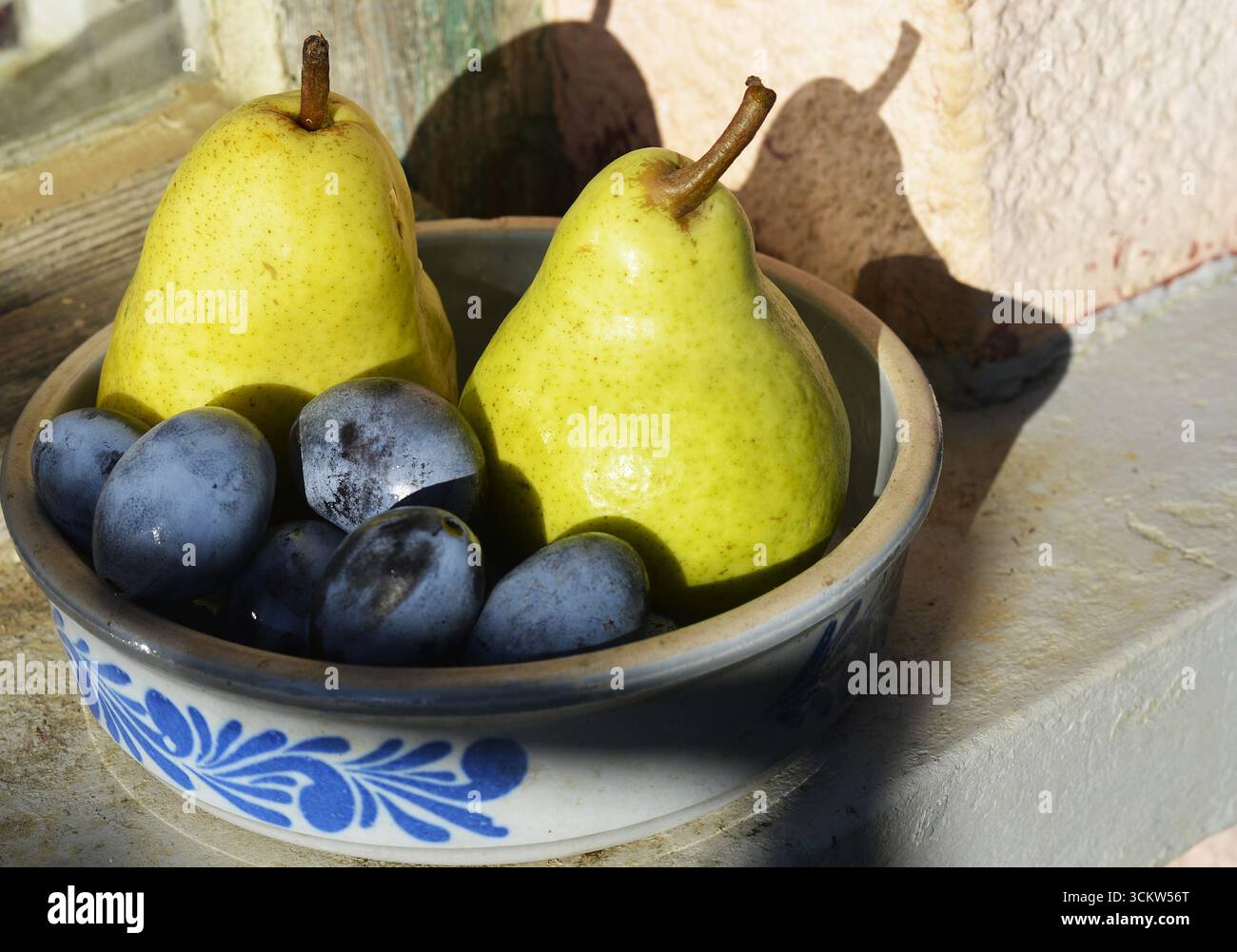 Poires et prunes dans un vieux pot en argile, photo de nature morte vintage Banque D'Images