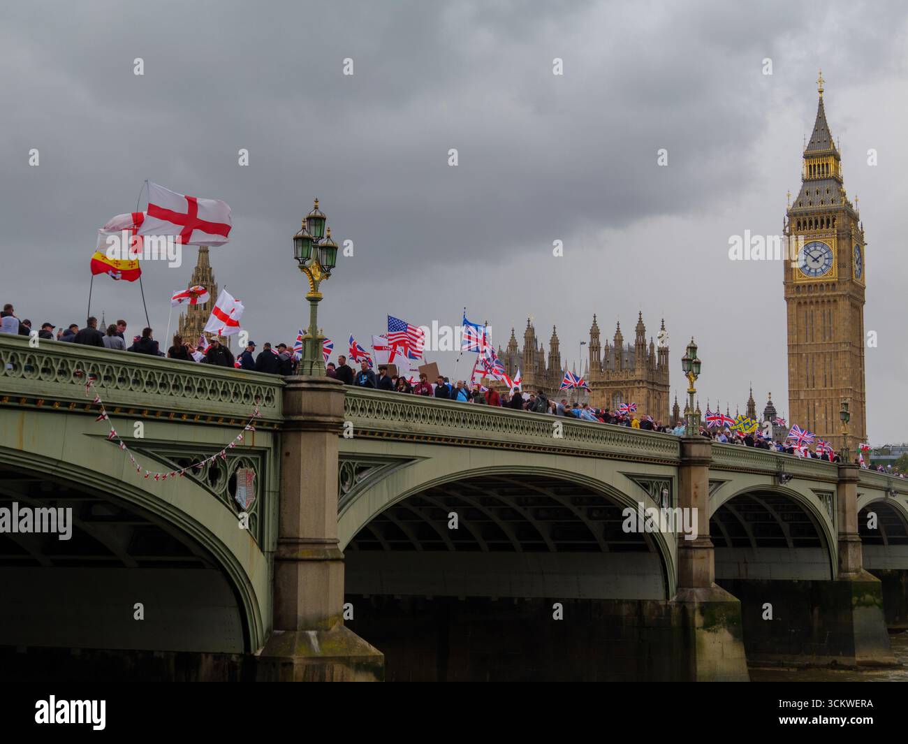 Manifestation unite the Kingdom, 13 septembre 2025, Westminster, Londres, Royaume-Uni. Des manifestants arborant les drapeaux de l'Union Jack et de St George défilent dans le centre de Londres à travers le pont de Westminster avec Big Ben en arrière-plan lors d'une manifestation organisée par Tommy Robinson Banque D'Images