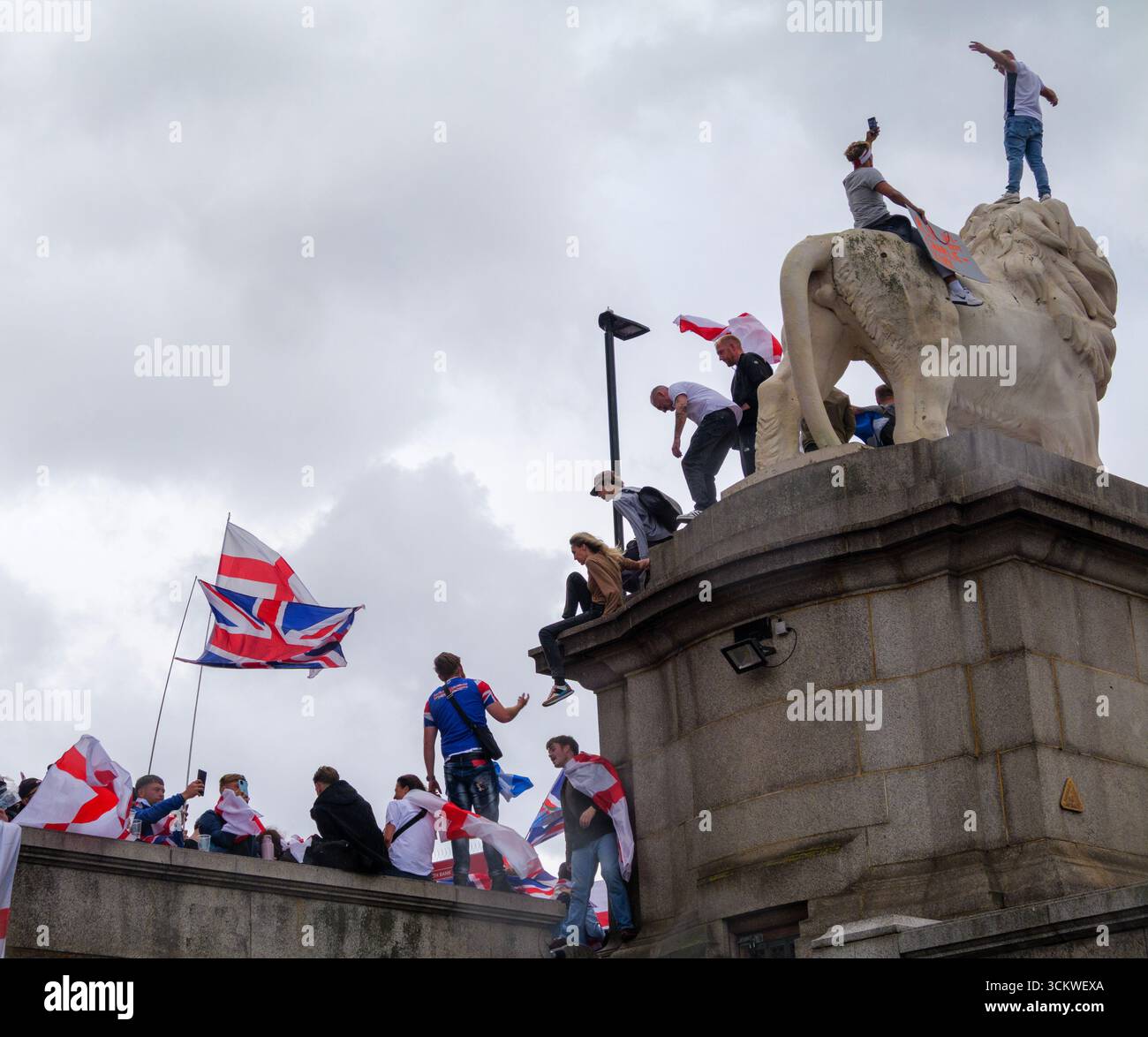 Manifestation unite the Kingdom, 13 septembre 2025, Westminster, Londres, Royaume-Uni. Des manifestants arborant les drapeaux de l'Union Jack et de St George grimpent le Lion de South Bank sur le pont de Westminster dans le centre de Londres lors d'une manifestation organisée par Tommy Robinson Banque D'Images