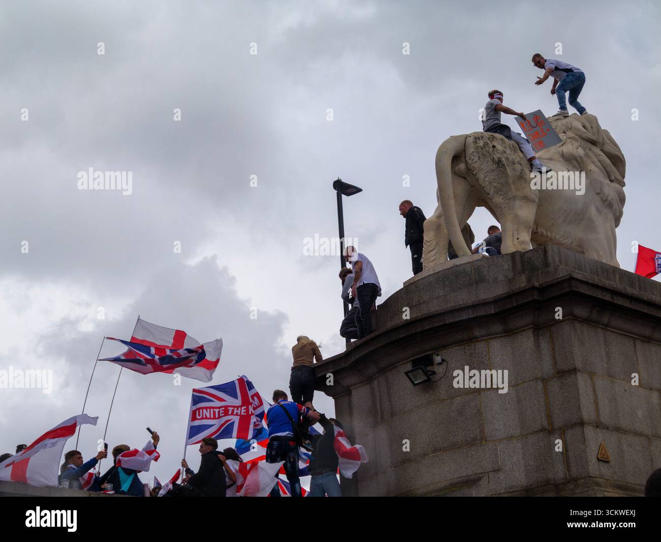 Manifestation unite the Kingdom, 13 septembre 2025, Westminster, Londres, Royaume-Uni. Des manifestants arborant les drapeaux de l'Union Jack et de St George grimpent le Lion de South Bank sur le pont de Westminster dans le centre de Londres lors d'une manifestation organisée par Tommy Robinson Banque D'Images