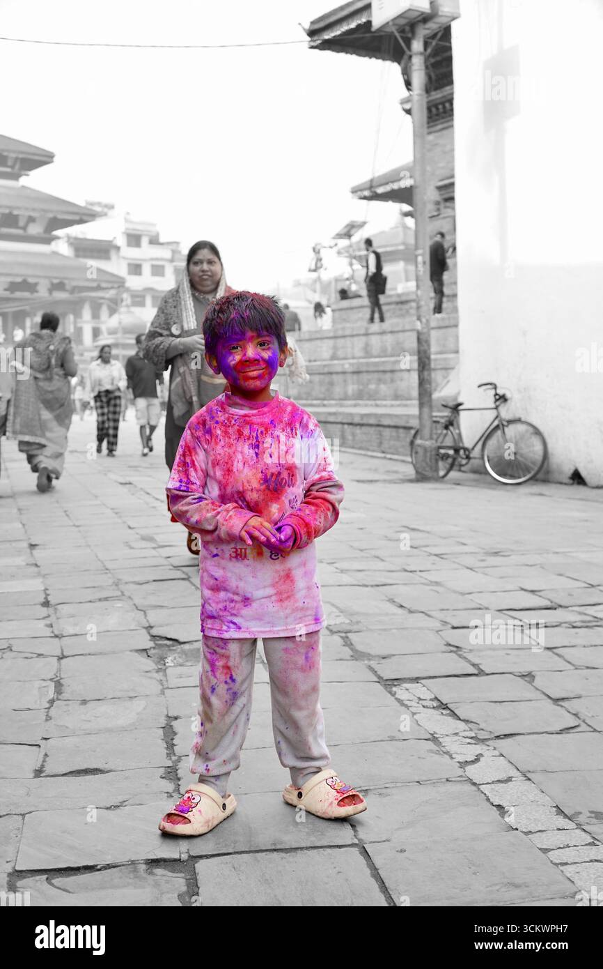 Enfant souriant couvert de couleurs vives pendant le festival Holi à Katmandou, Népal Banque D'Images