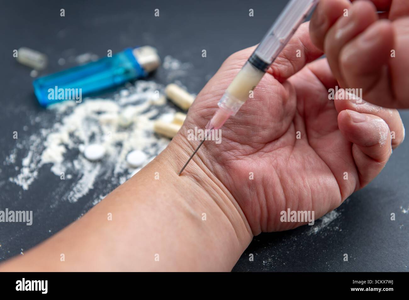 Une prise de drogue illégale, concept de dépendance avec une personne injectant une substance dans le bras à l'aide d'une seringue médicale, et un comprimé plus léger et écrasé dans le th Banque D'Images