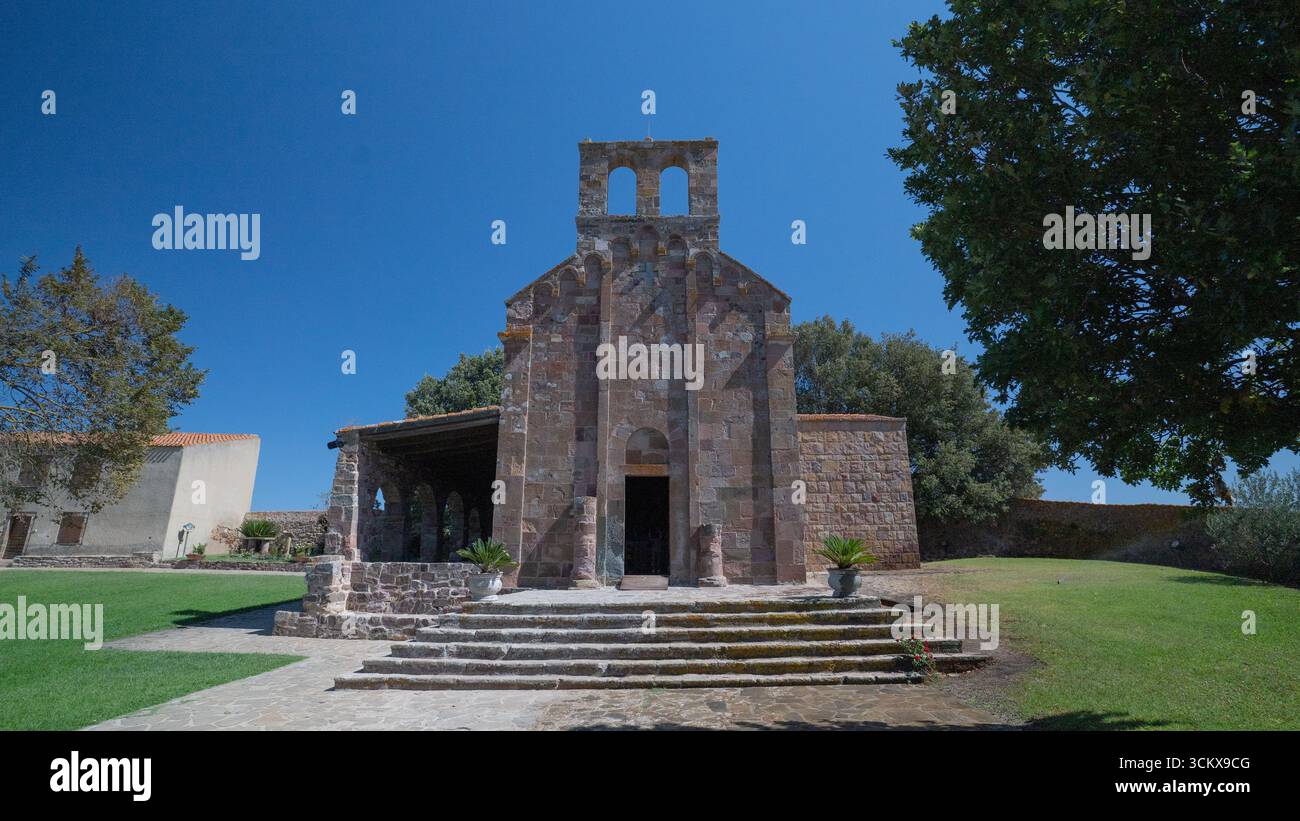 Façade d'église en pierre romane avec pignon de cloche sous ciel bleu clair à Oschiri Banque D'Images