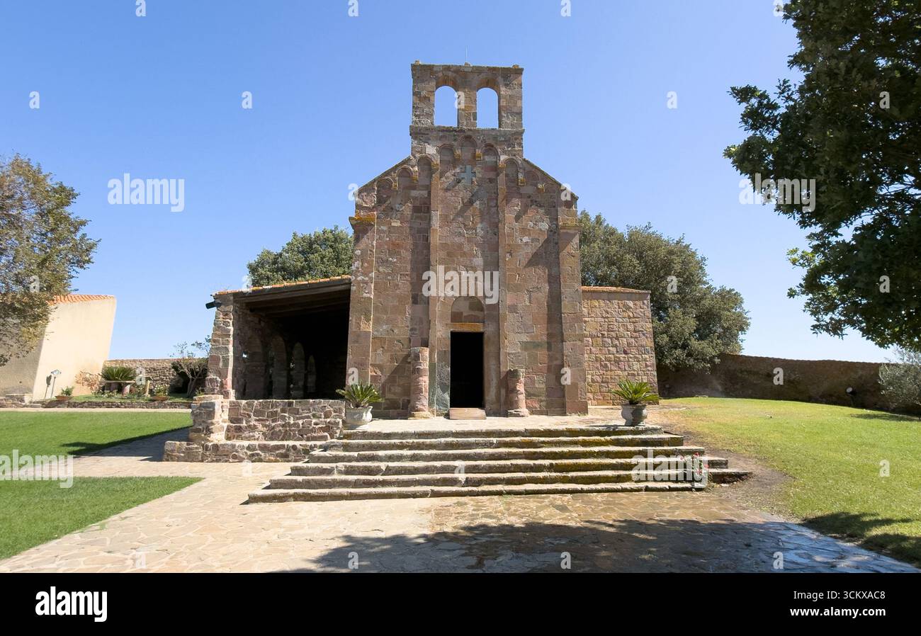 Façade d'église en pierre romane avec pignon de cloche sous ciel bleu clair à Oschiri Banque D'Images