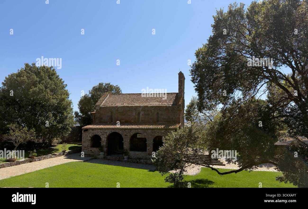 Façade d'église en pierre romane avec pignon de cloche sous ciel bleu clair à Oschiri Banque D'Images