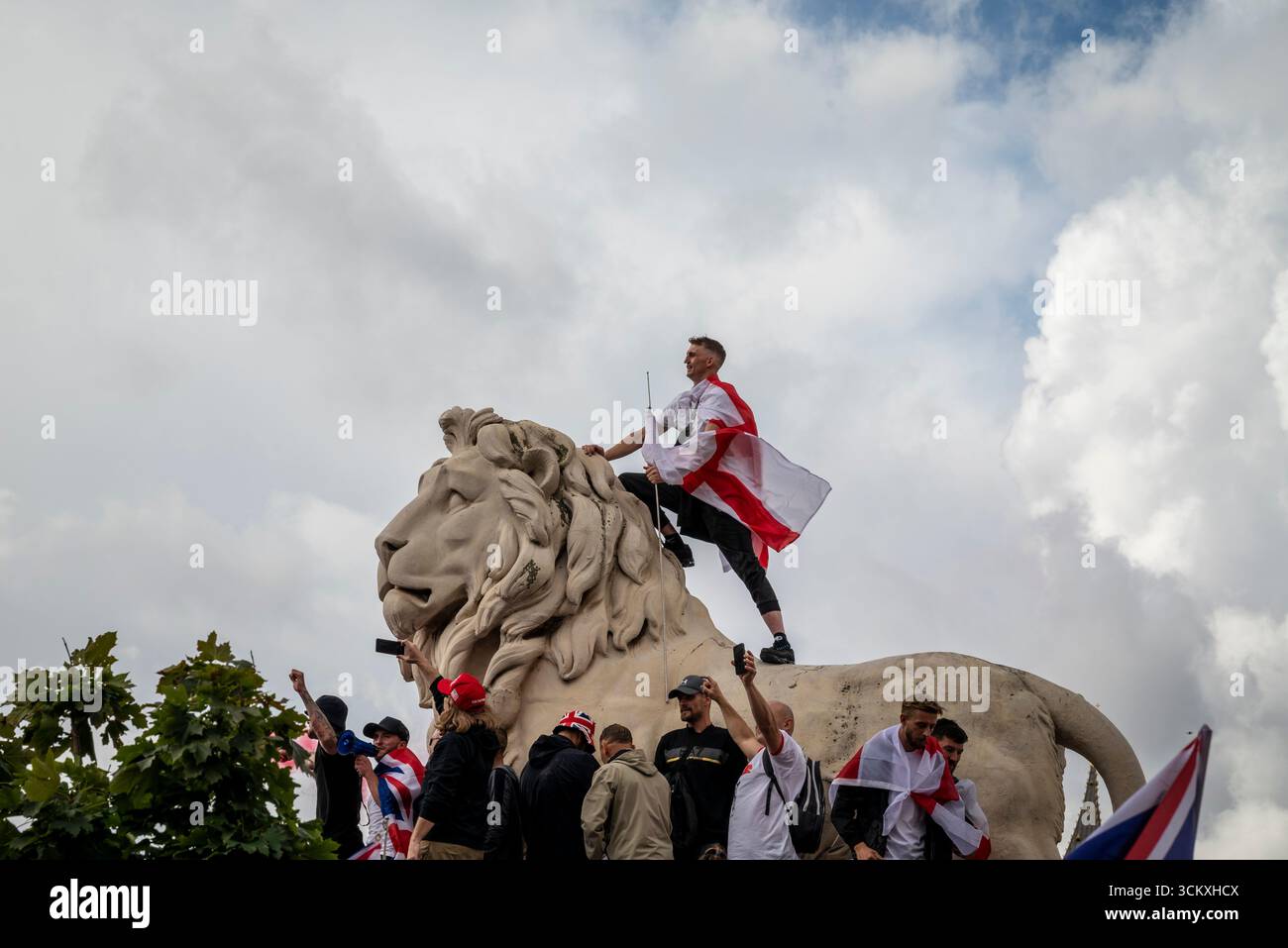 Protestataires au sommet d'un lion sur le pont de Westminster, la marche "Unite the Kingdom" menée par Tommy Robinson rassemble des centaines de milliers de manifestants en Centra Banque D'Images