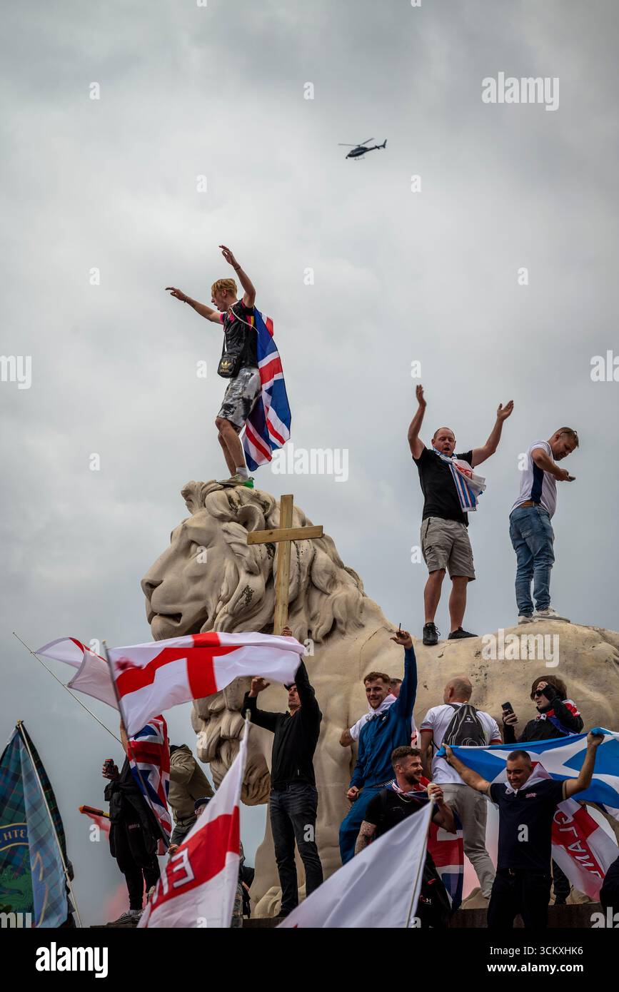 Protestataires au sommet d'un lion sur le pont de Westminster, la marche "Unite the Kingdom" menée par Tommy Robinson rassemble des centaines de milliers de manifestants en Centra Banque D'Images