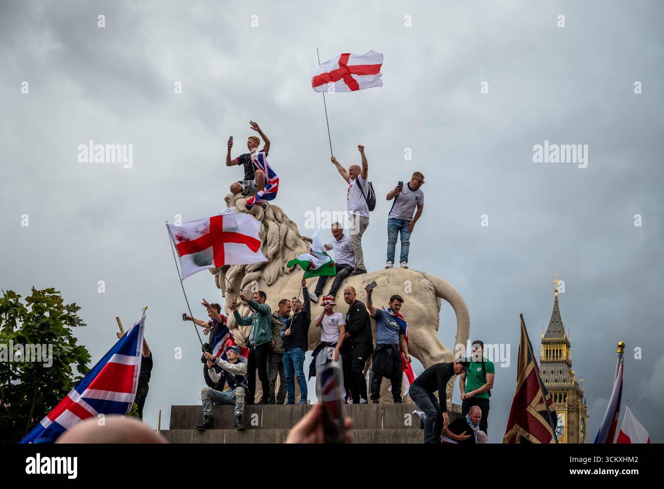 Protestataires au sommet d'un lion sur le pont de Westminster, la marche "Unite the Kingdom" menée par Tommy Robinson rassemble des centaines de milliers de manifestants en Centra Banque D'Images