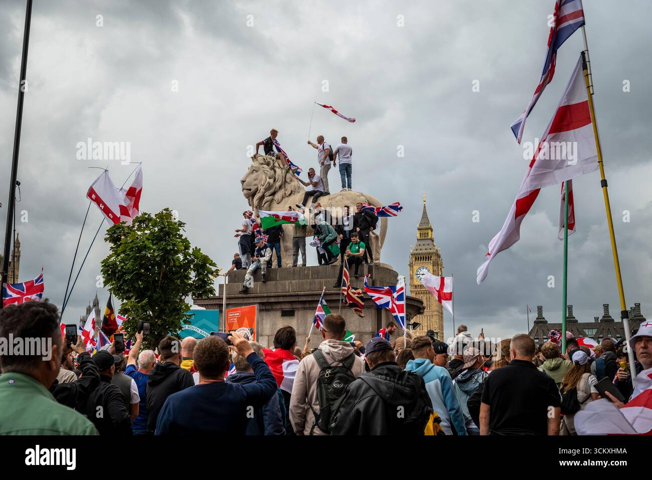 Protestataires au sommet d'un lion sur le pont de Westminster, la marche "Unite the Kingdom" menée par Tommy Robinson rassemble des centaines de milliers de manifestants en Centra Banque D'Images