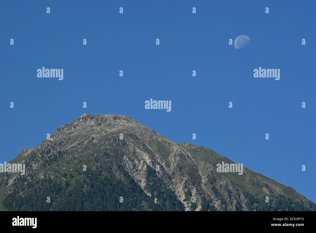Lune au-dessus de Mountain Peak dans un ciel d'été clair Banque D'Images Lune au-dessus de Mountain Peak dans un ciel d'été clair Banque D'Images