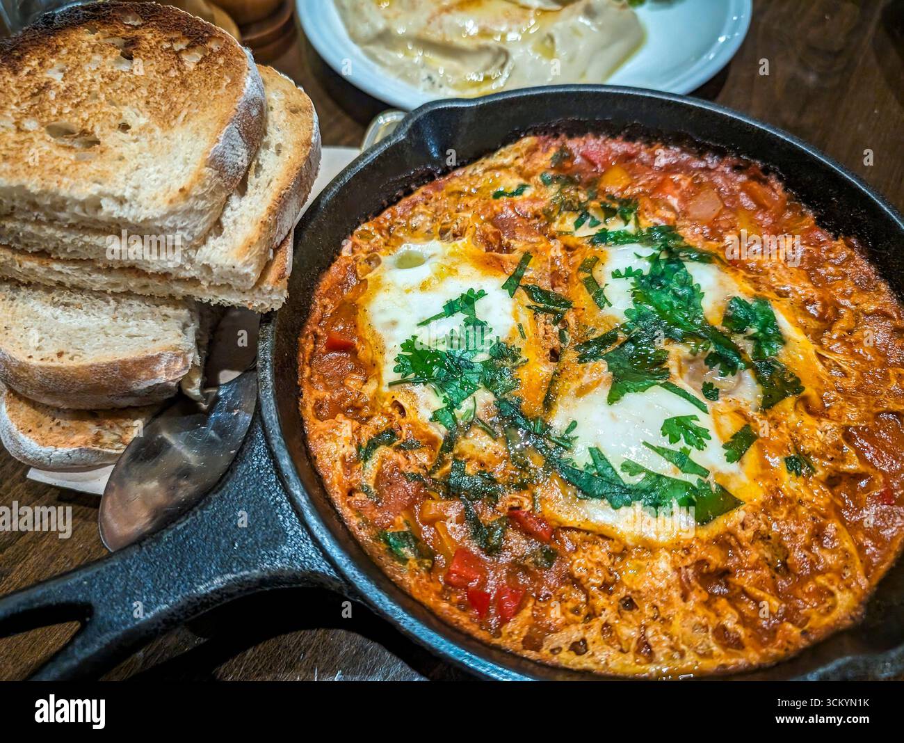 Vue de dessus de shakshouka, œufs pochés dans une sauce tomate servis dans une poêle avec du pain sur une table à manger dans un restaurant local à Riyad, Arabie Saoudite Banque D'Images