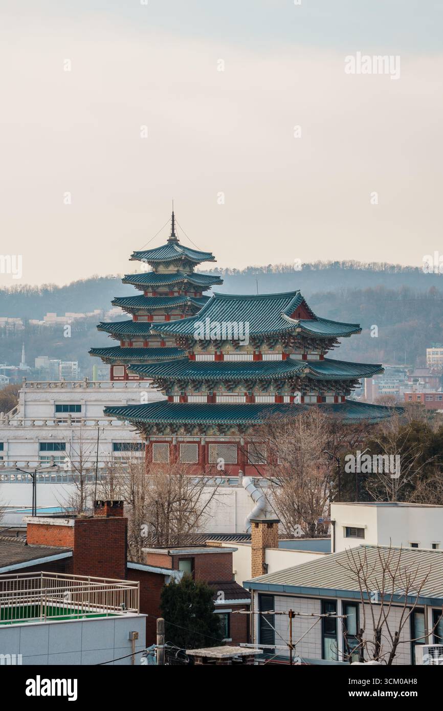 Vue surélevée de la pagode du Musée folklorique national de Corée avec son toit en tuiles bleues, s'élevant au-dessus des bâtiments urbains de Séoul et des collines lointaines. Banque D'Images