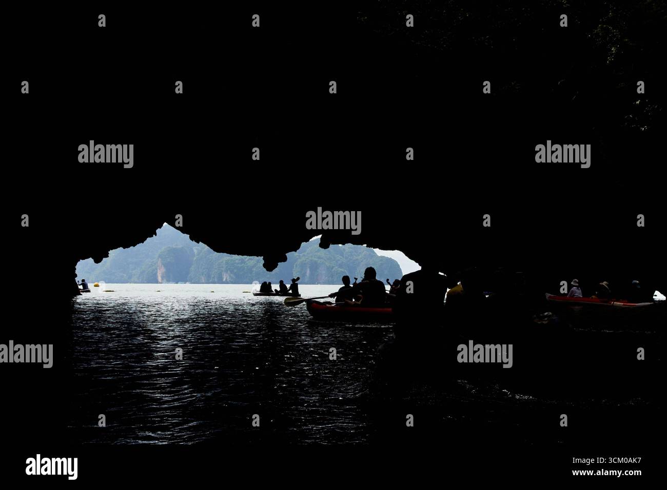 PHUKET, THAÏLANDE - 12 NOVEMBRE 2017 : silhouette de personnes faisant du kayak à travers une grotte calcaire surplombant la mer ouverte en plein jour. Banque D'Images