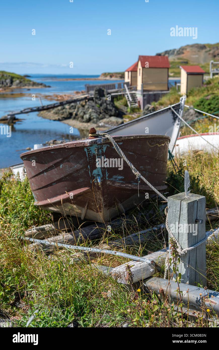 Un dory attaché sur le rivage avec des étapes de pêche en arrière-plan près de Back Harbour, Terre-Neuve Banque D'Images