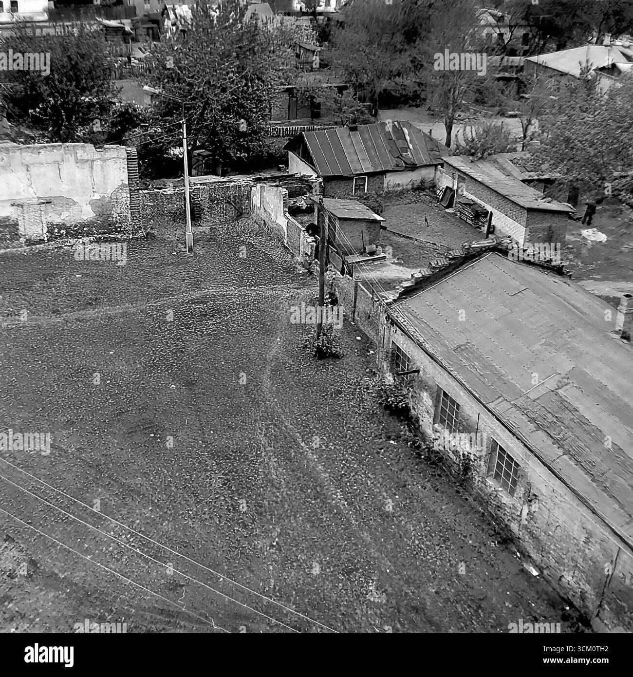 Les coulisses d'un grand projet de reconstruction : cours intérieures chaotiques et secteur du logement privé derrière la place centrale de Sloviansk, 1975-1976. Le cliché capture de vieilles maisons destinées à la démolition, des hangars, des débris. Cette image reflète le processus de déminage du site pour la rénovation urbaine, symbolisant une époque révolue sacrifiée pour la nouvelle vision monumentale d'une ville soviétique, et documente la vie complexe mais paisible dans le Donbass pendant cette période Banque D'Images