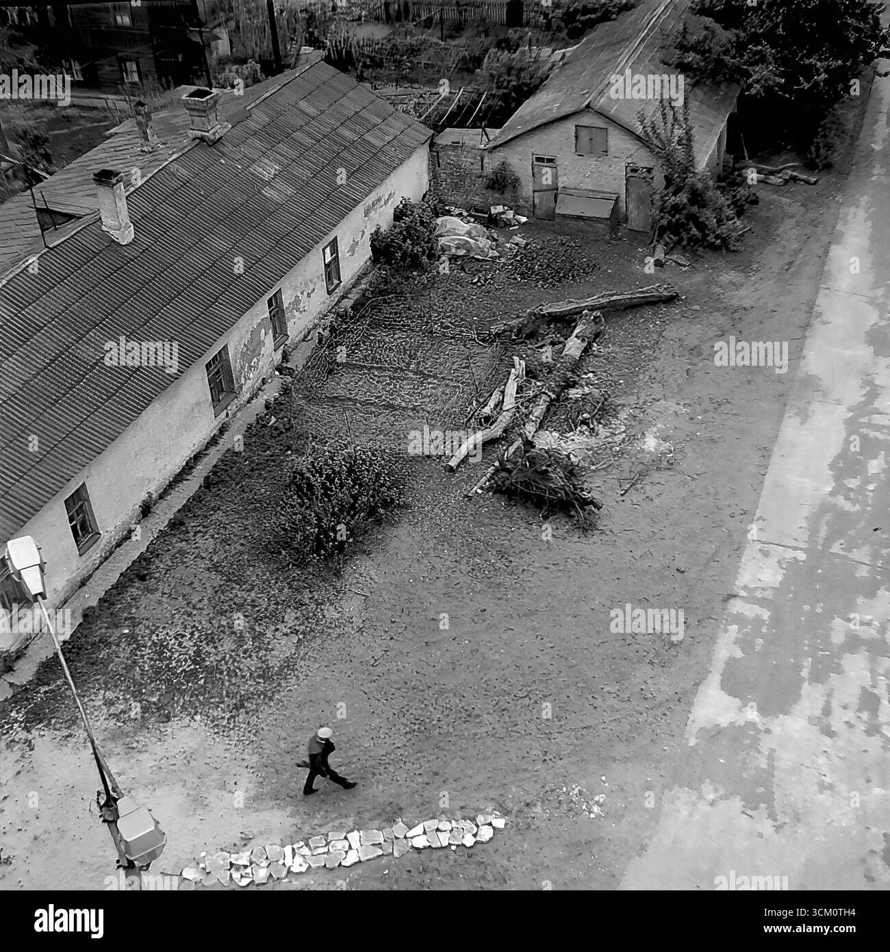 Les coulisses d'un grand projet de reconstruction : cours intérieures chaotiques et secteur du logement privé derrière la place centrale de Sloviansk, 1975-1976. Le cliché capture de vieilles maisons destinées à la démolition, des hangars, des débris. Cette image reflète le processus de déminage du site pour la rénovation urbaine, symbolisant une époque révolue sacrifiée pour la nouvelle vision monumentale d'une ville soviétique, et documente la vie complexe mais paisible dans le Donbass pendant cette période Banque D'Images