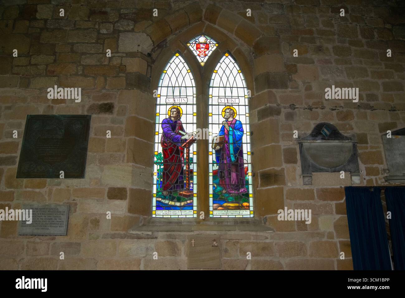 Les vitraux vibrants représentent des personnages religieux, illuminant les murs de pierre anciens de l'église Sainte-Marie-la-Vierge à Leake. Banque D'Images