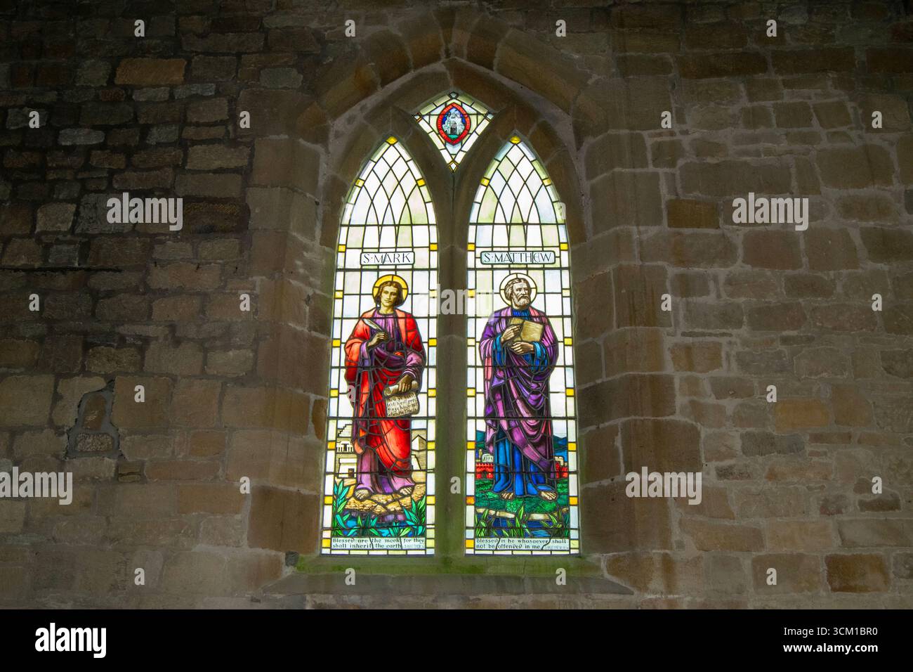 Les vitraux vibrants représentent des personnages religieux, illuminant les murs de pierre anciens de l'église Sainte-Marie-la-Vierge à Leake. Banque D'Images