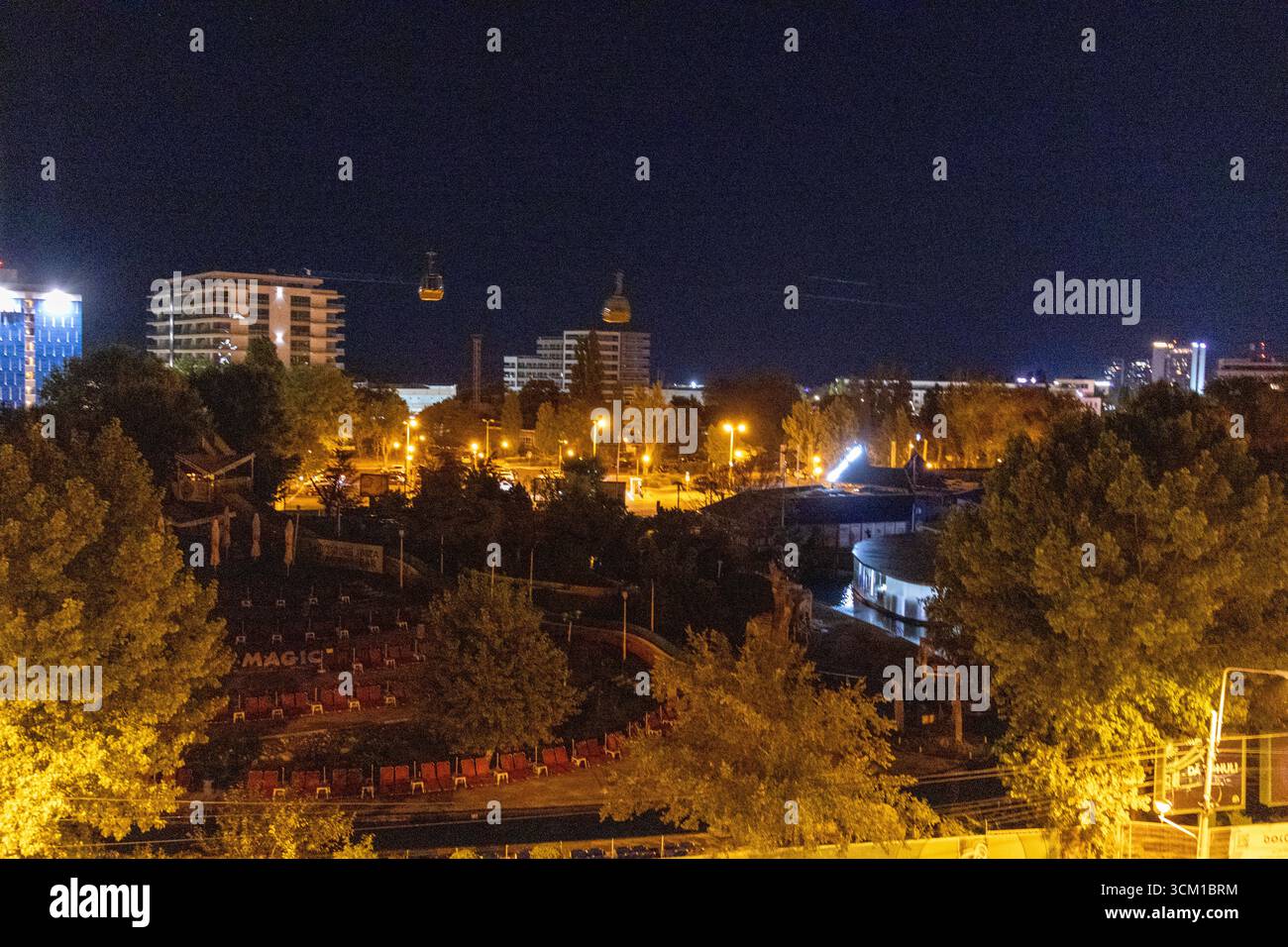 Paysage urbain nocturne avec des rues, des bâtiments et des arbres très éclairés sous un ciel sombre et clair Banque D'Images
