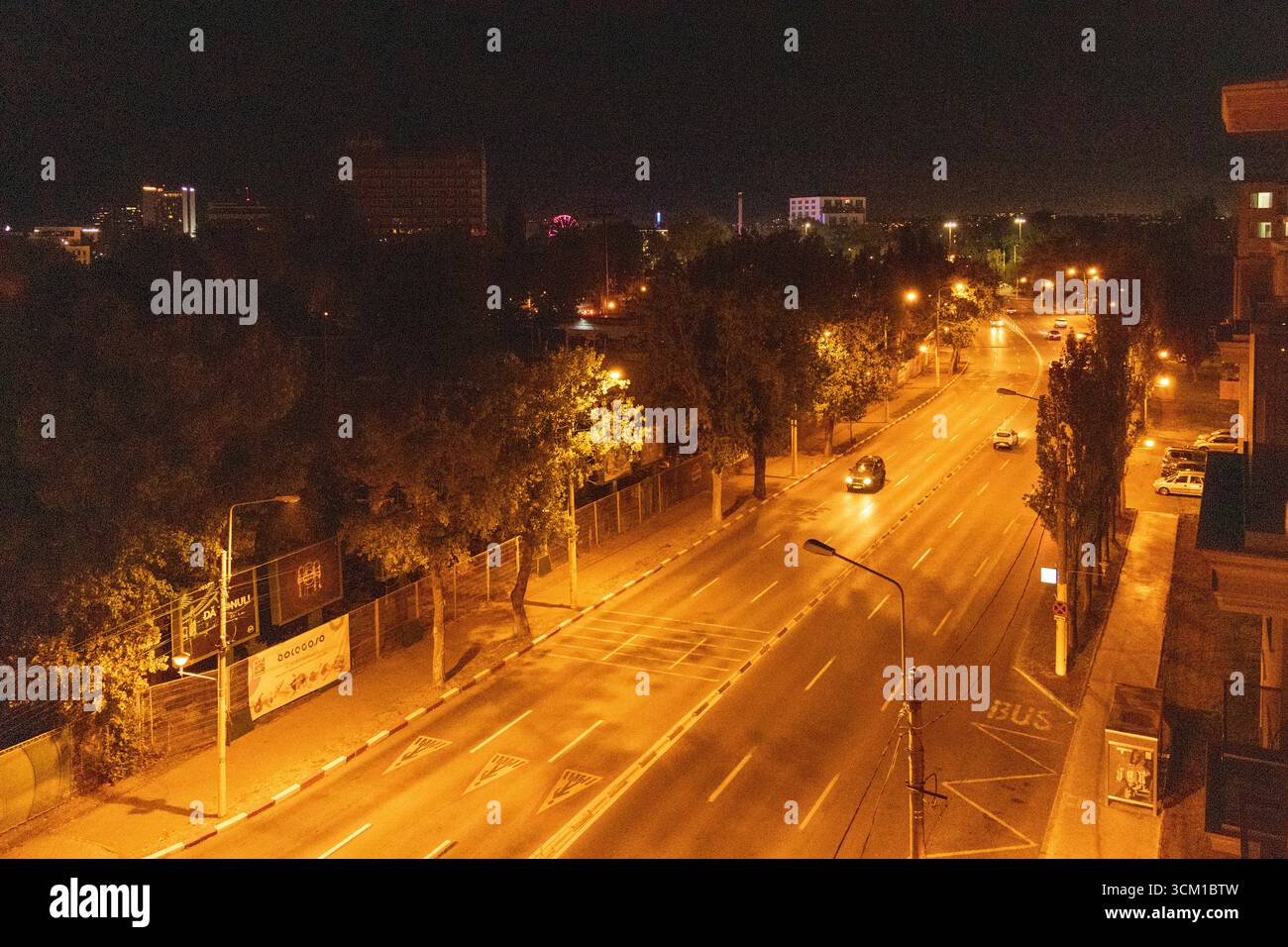 Paysage urbain nocturne avec des rues, des bâtiments et des arbres très éclairés sous un ciel sombre et clair Banque D'Images