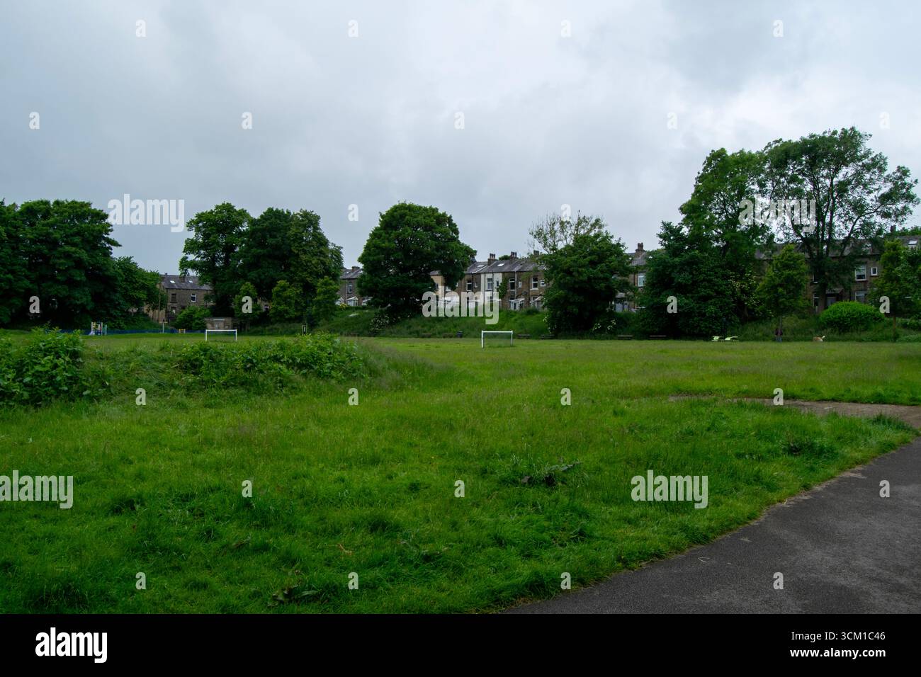 Vastes terrains verts et buts de football au Beech Recreation Ground, avec des maisons résidentielles et des arbres matures bordant l'arrière-plan. Banque D'Images