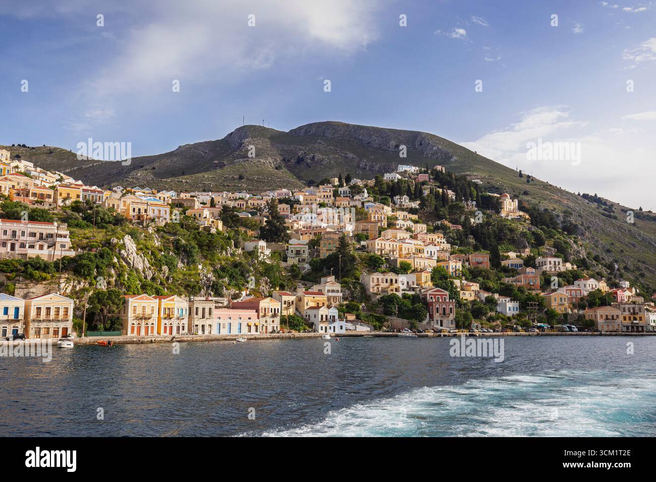 Bâtiments colorés sur une colline dans la ville idyllique de Symi au bord de la mer Égée sur l'île de Symi (Simi, Syme) en Grèce par une journée ensoleillée. Banque D'Images