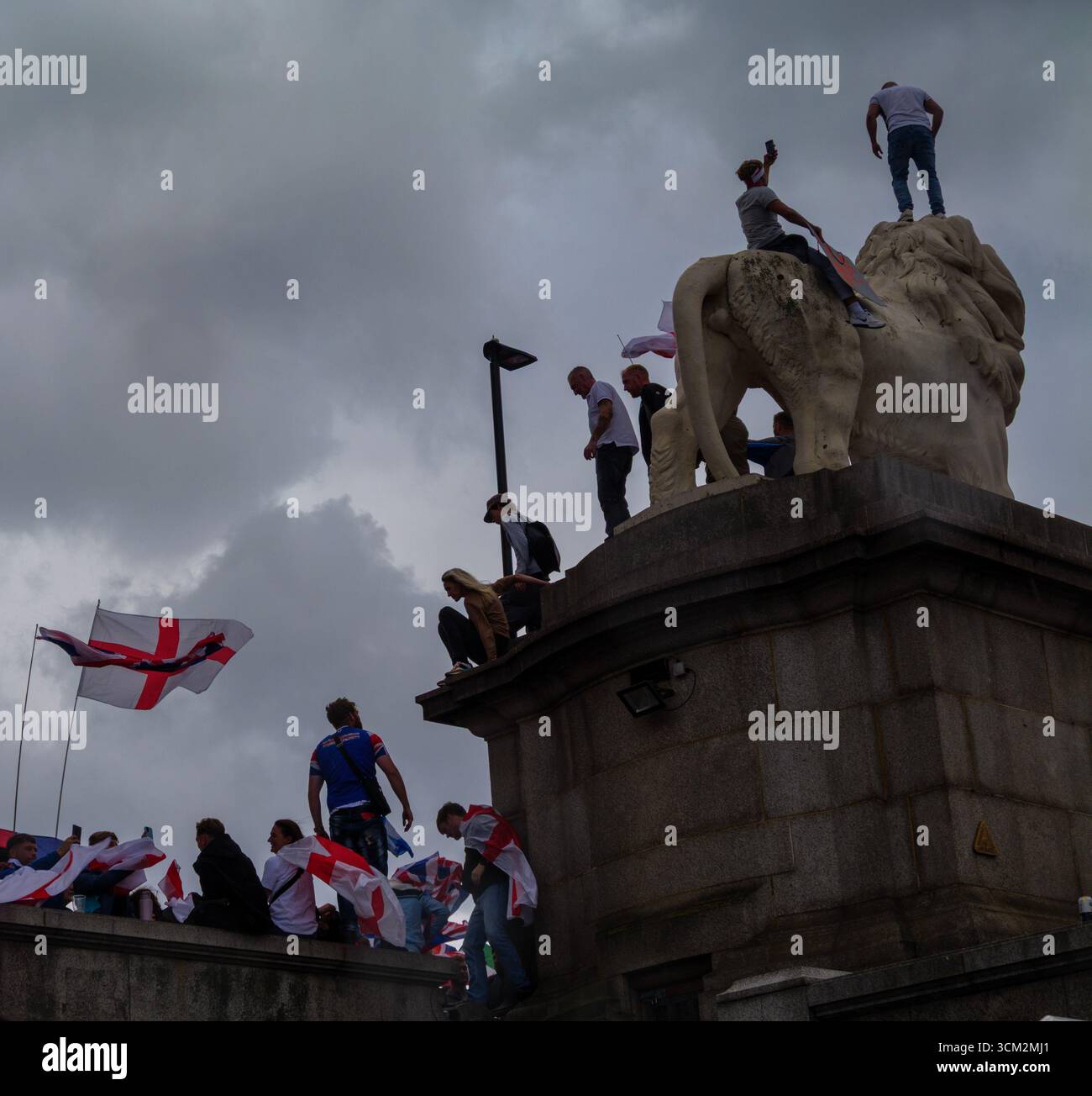 Manifestation unite the Kingdom, 13 septembre 2025, Westminster, Londres, Royaume-Uni. Sous des nuages sombres, des manifestants arborant les drapeaux de l'Union Jack et de St George grimpent le Lion de South Bank sur le pont de Westminster dans le centre de Londres lors d'une manifestation organisée par Tommy Robinson Banque D'Images