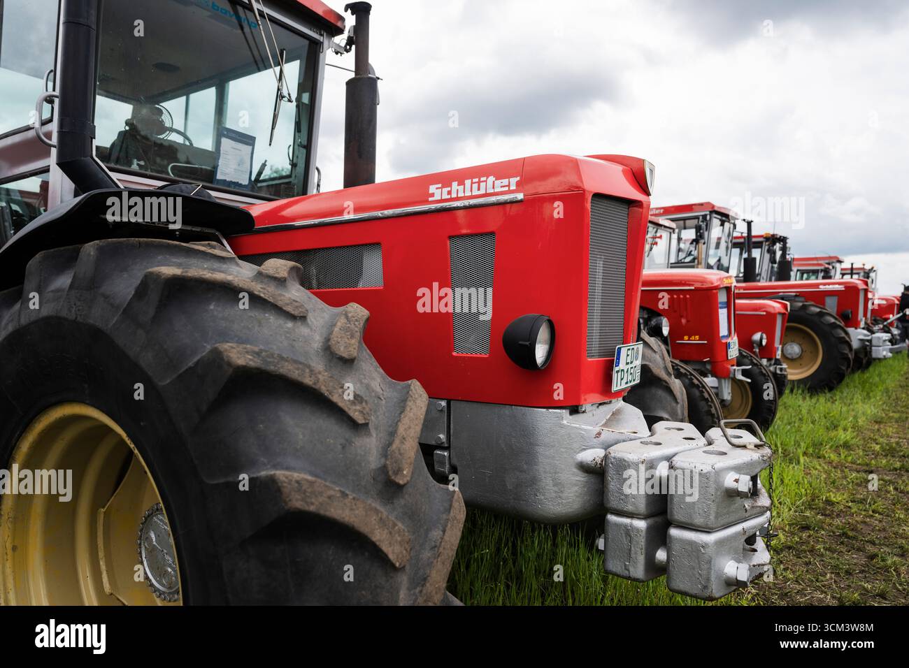 Logo et signalisation sur le capot d'un tracteur Schlüter rouge devant d'autres camions Schlüter historiques, Hallbergmoos, Bavière, Allemagne Banque D'Images