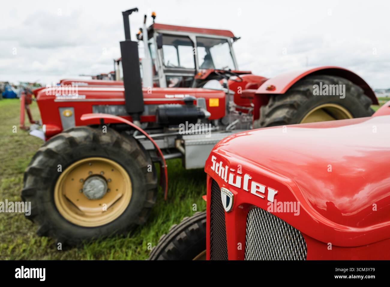 Logo et signalisation sur le capot d'un tracteur Schlüter rouge devant d'autres camions Schlüter historiques, Hallbergmoos, Bavière, Allemagne Banque D'Images
