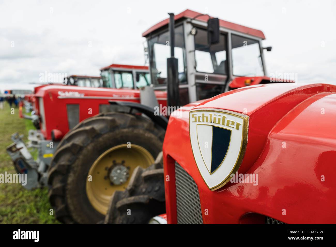 Logo et signalisation sur le capot d'un tracteur Schlüter rouge devant d'autres camions Schlüter historiques, Hallbergmoos, Bavière, Allemagne Banque D'Images