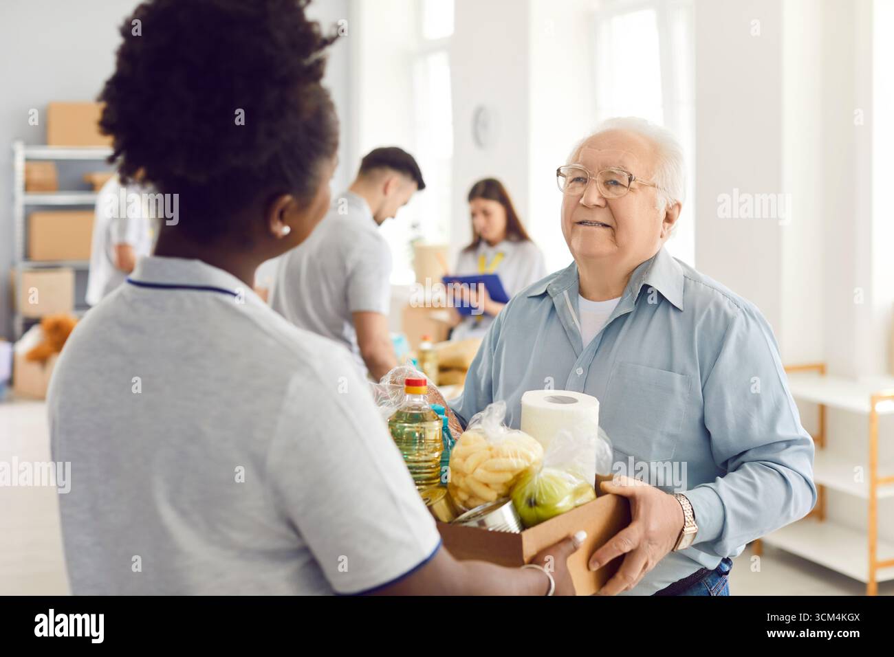 Giving Help, jeune groupe bénévole travaillant dans la fondation caritative alimentaire, faire un don aux vieux nécessiteux Banque D'Images