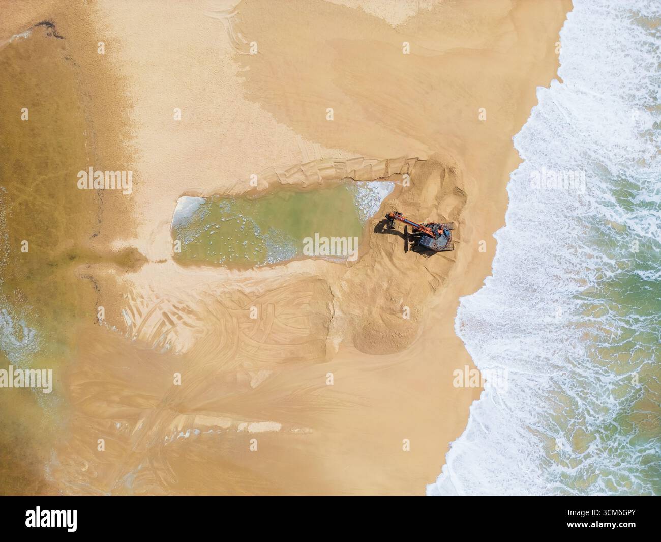 Vue aérienne d'engins de terrassement ouvrant un canal d'eau d'un lac à l'océan à Currimundi sur le Sunshine Caost dans le Queensland, Australie Banque D'Images